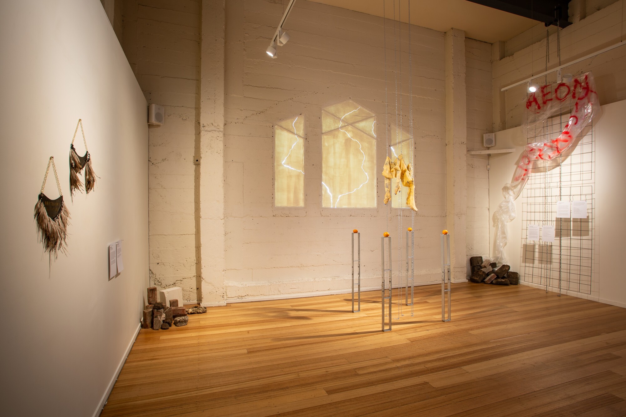 Installation view of <em>Aeon Resurrection</em>, 2022. Ange Jeffrey, Brothaboy Sistagirl, 2021. Brass, emu feathers, hemp, brass black; Ange Jeffrey, Murru, 2021. Brass, emu feathers, hemp, sterling silver; Em Finucane, The Body as a Space we Inhabit, 2019. Latex, acrylic nails, ballpoint pen, oranges, incense sticks, architectural anchors. Image courtesy of the gallery. Photo: Lucy Foster