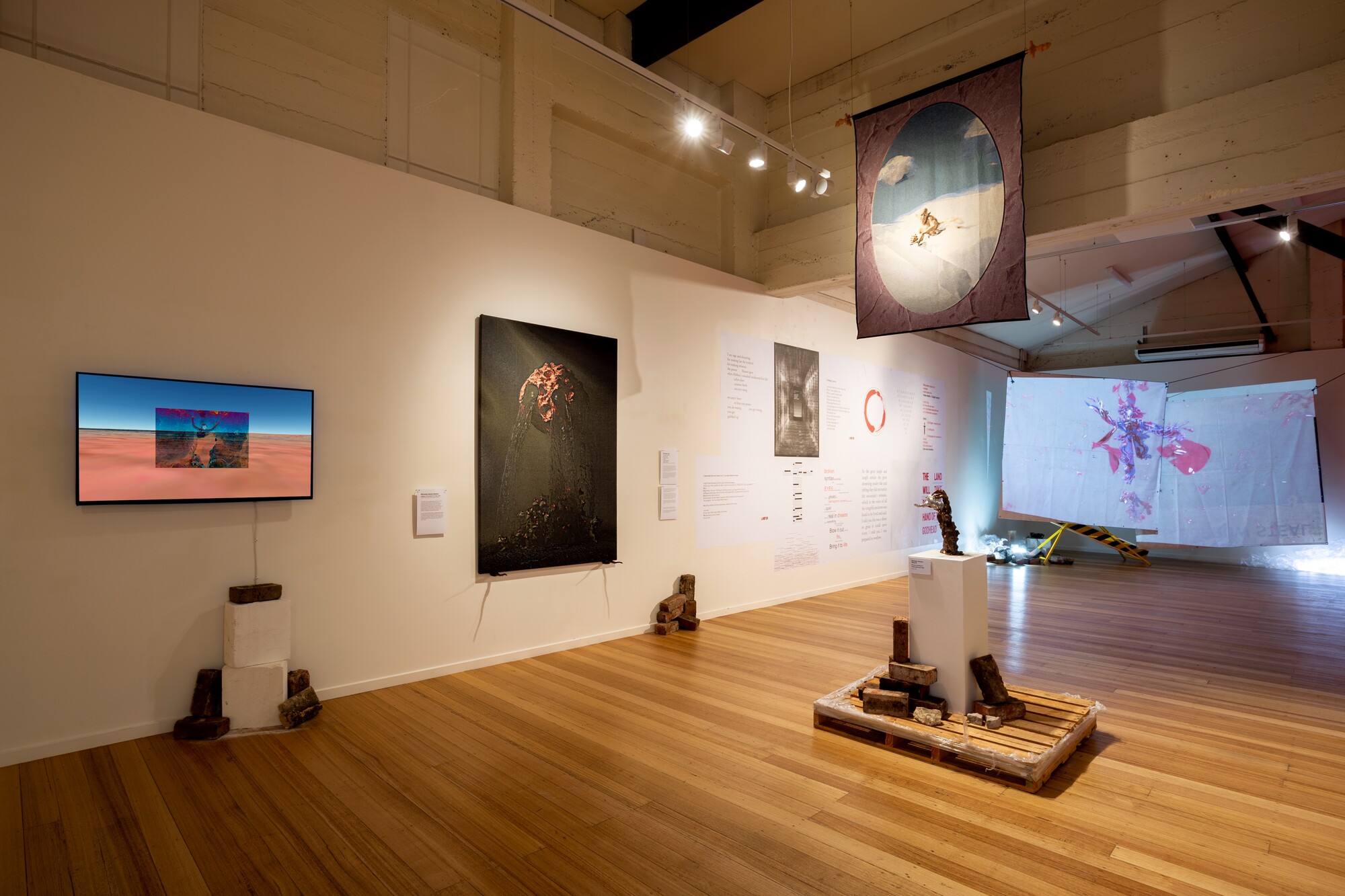 Installation view of <em>Aeon Resurrection</em>, 2022. Jahkarli Romanis, <em>Cache,</em> 2022. Video, 3 mins; Nicholas Aloisio-Shearer, <em>Reject Modernity, Embrace Tradition II: I Have Been In This Place Before,</em> 2021. Jacquard woven tapestry, silicon, pigment, aluminium, resin and bronze pigment; Nicholas Aloisio-Shearer, Allegory of the Death of Cringe, 2021. Jacquard woven tapestry, silicon, pigment and aluminium; Huntrezz Janos, <em>video,</em> 2022. 3D video animation. Courtesy the gallery. Photo: Lucy Foster