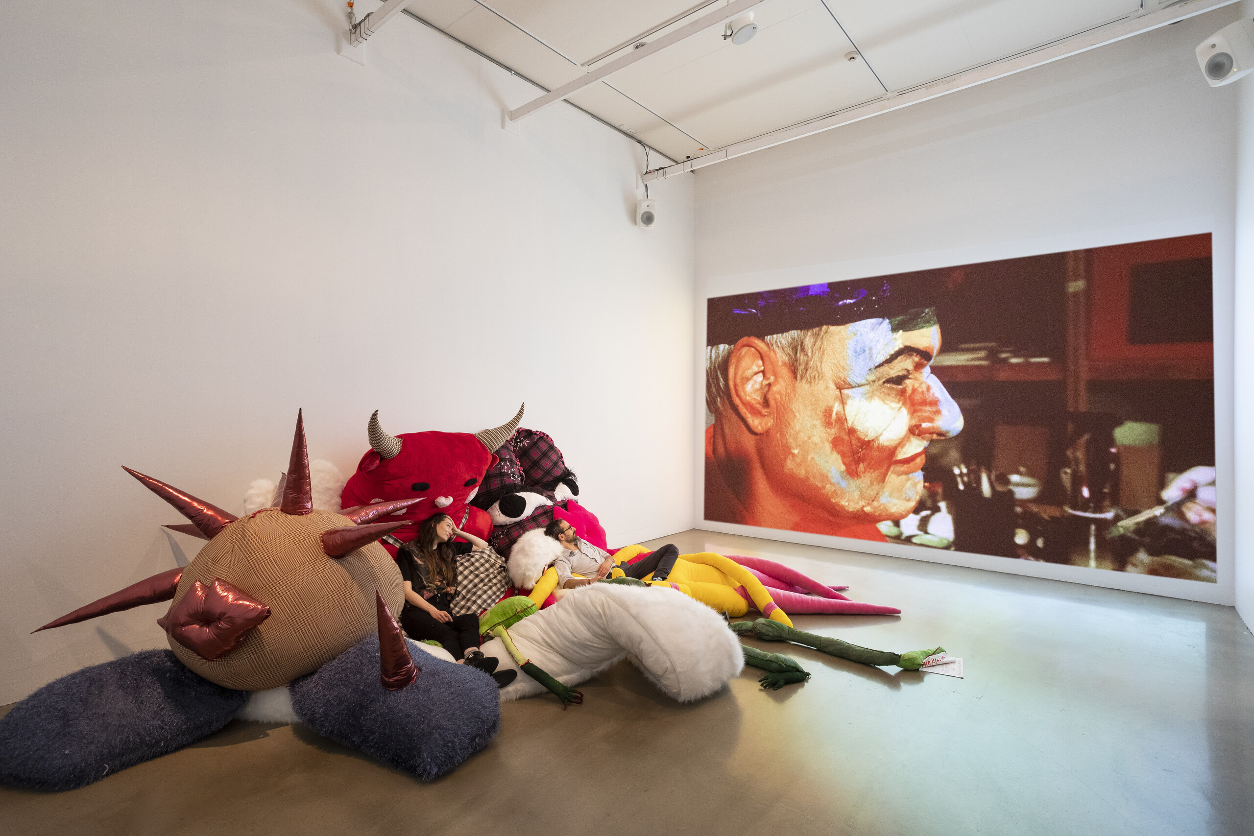 Installation view of <em>Agent Bodies</em> 2022. The Killing, <em>6-Pack</em>, 2022. Mixed textiles and synthetic fibres; Mike Parr, <em>La Triviata/Bad Son</em>, 2010-2013. Digital video (11:50). Image courtesy of RMIT Gallery. Photo: Tobias Titz