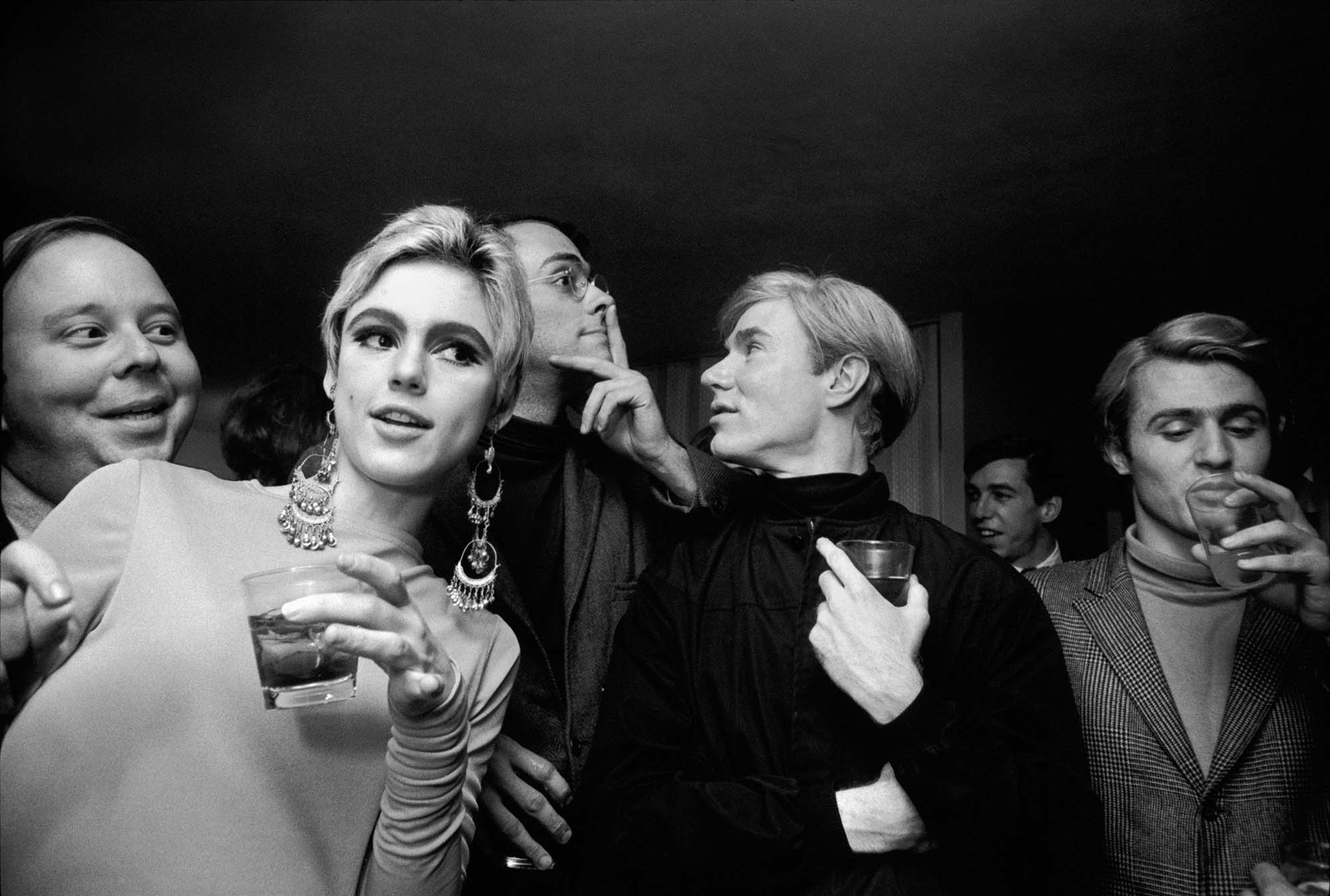 Steve Schapiro, born Brooklyn, New York, United States 1934, died Chicago, Illinois, United States 2022, <em>Edie Sedgwick, Andy Warhol, and others at a party,</em> 1965, New York, gelatin-silver photograph, 31.5 x 47.1 cm (image), 40.0 x 49.9 cm (sheet); Courtesy of Fahey/Klein Gallery, © estate of Steve Schapiro