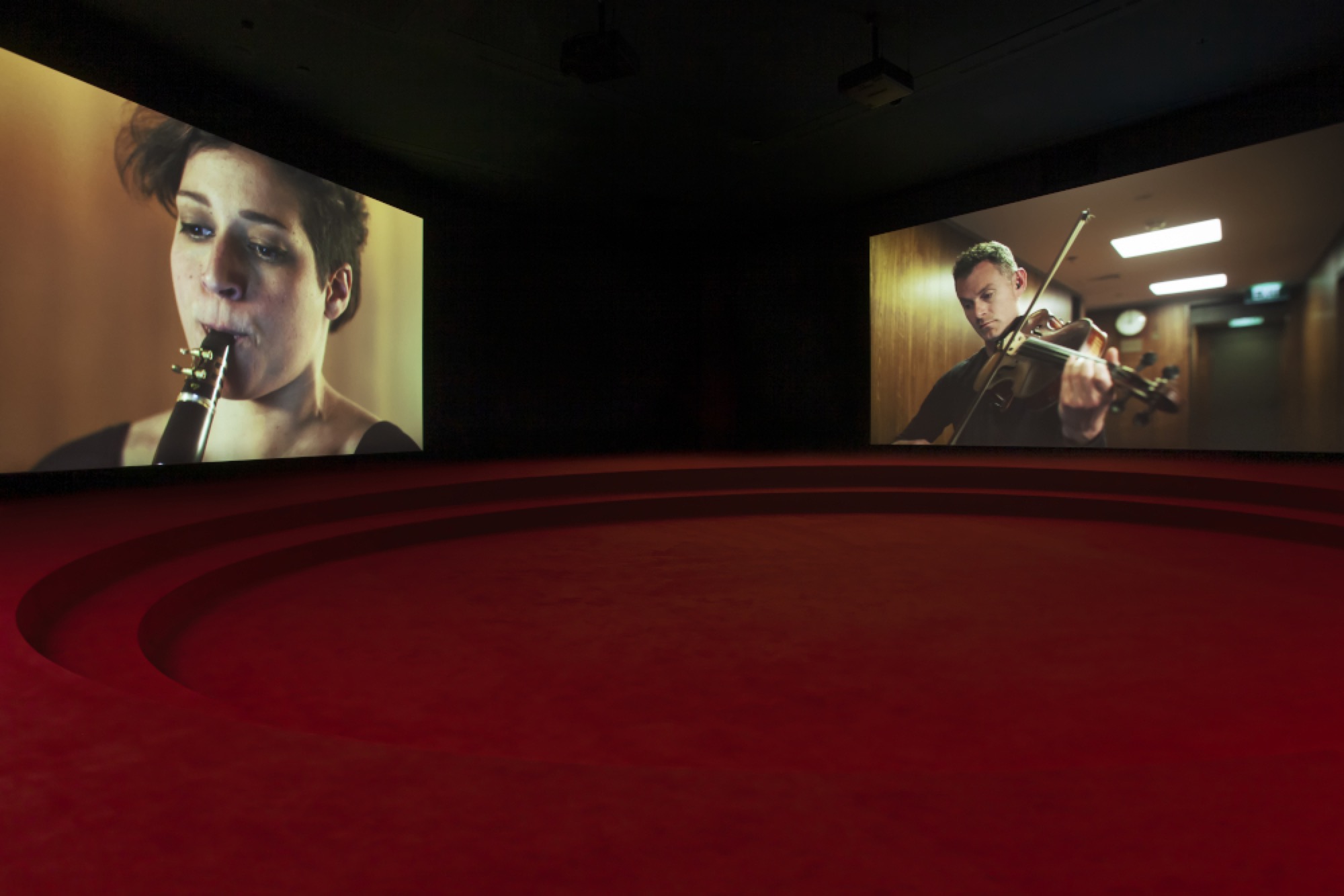 Angelica Mesiti, <em>ASSEMBLY</em>, 2019 (installation shot) three-channel video installation in architectural amphitheater. HD video projections, color, six-channel mono sound, 25 mins, dimensions variable. © Photography: Josh Raymond. Commissioned by the Australia Council for the Arts on the occasion of the 58th International Art Exhibition–La Biennale di Venezia. Courtesy of the artist and Anna Schwartz Gallery, Australia and Galerie Allen, Paris.