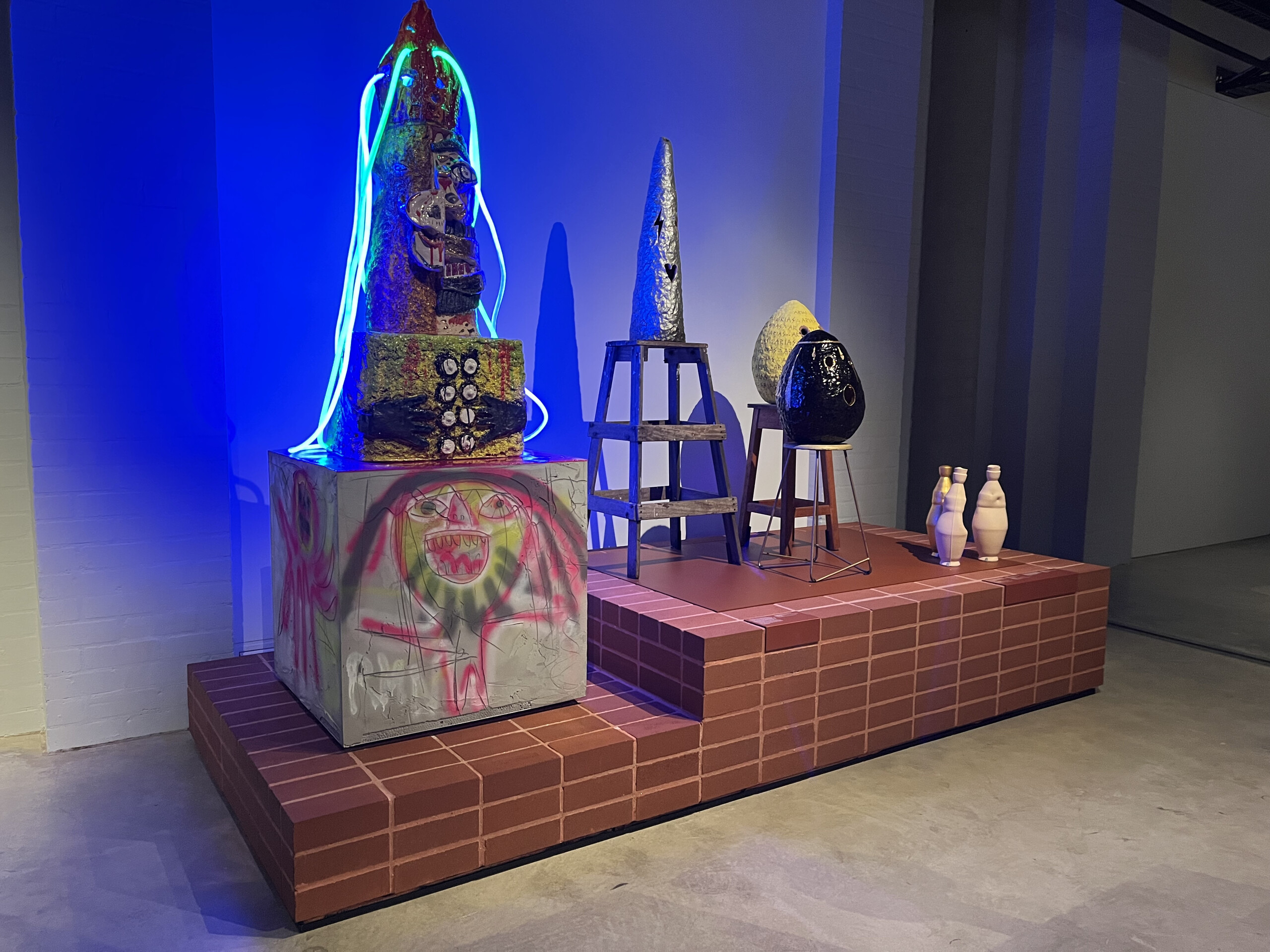 Installation view of Ramesh Mario Nithiyendran, <em>Hog/Human</em>, earthenware, mixed media, 2019 (left) and, Nell, three works <em>the Saxophone, yes</em> Nell, ARIAS 2017, painted earthenware and wood, 2016-2017, Sydney (right). Photo: Victoria Pham