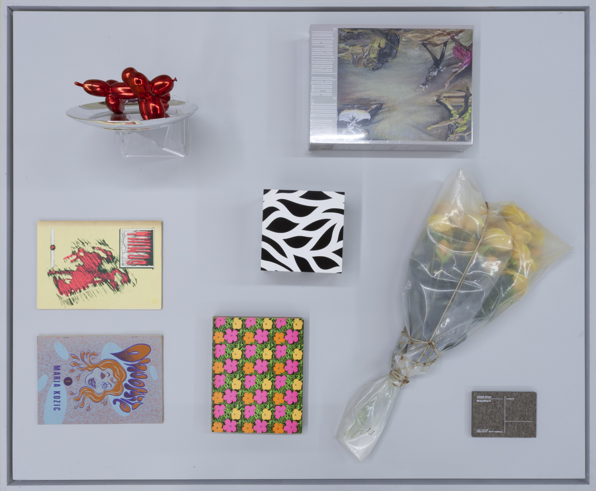 Cabinet view, <em>Collectables</em>, Centre D’editions, Gertrude St. From top left, counter-clockwise: Jeff Koons, <em>Ballon Dog Plate (Red)</em>, 1995; Maria Kozic, <em>Things</em> (Issue 4), 1989; Maria Kozic, <em>Dynamite I</em>, 1991; Andy Warhol, <em>Andy Warhol</em>, Moderna Museum, 1969; Sol LeWitt, <em>Loopy Doopy Box</em>, 1999; Jana Euler, <em>international dance 1000 pieces</em>, 2021; Christo and Jeanne-Claude, <em>Wrapped Roses</em>, 1968; Joseph Beuys, <em>Filzpostkarte</em>, 1985. Photo courtesy of Centre D’editions.