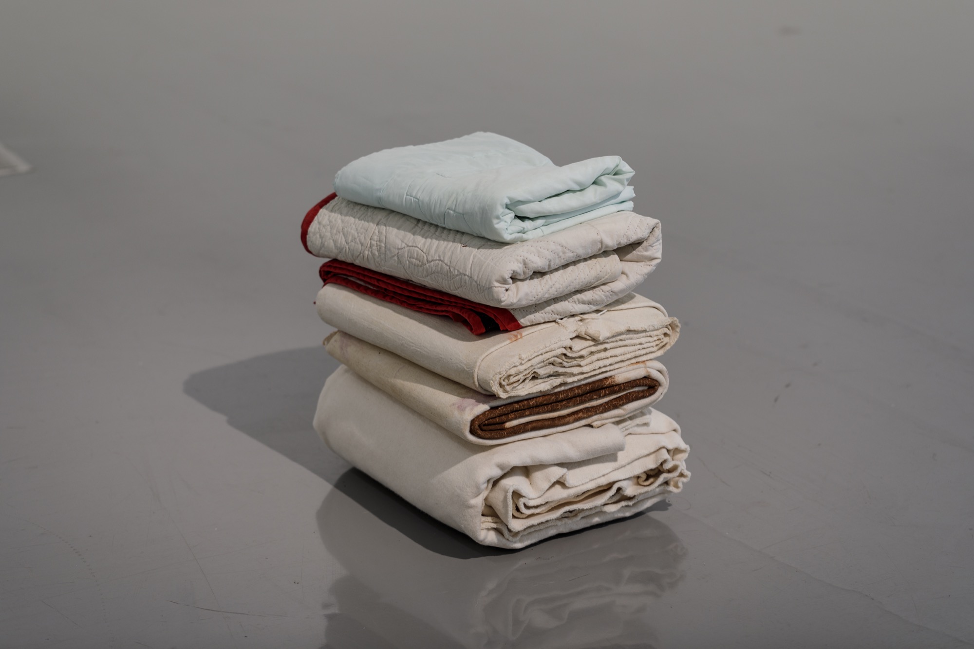 Kate Harding, <em>Birth and ten-year-old quilts</em> 2021 and Dale Harding, <em>Cloaks (mortua and mortuus)</em> 2018, <em>Repression cloak (ceremony for a gay wedding)</em> 2018 and <em>Untitled cloak</em> 2018. Installation view, <em>Dale Harding: Through a lens of visitation</em>, Monash University Museum of Art, Melbourne, 2021. Photo: Andrew Curtis. Image courtesy of the artist and Milani Gallery, Brisbane.