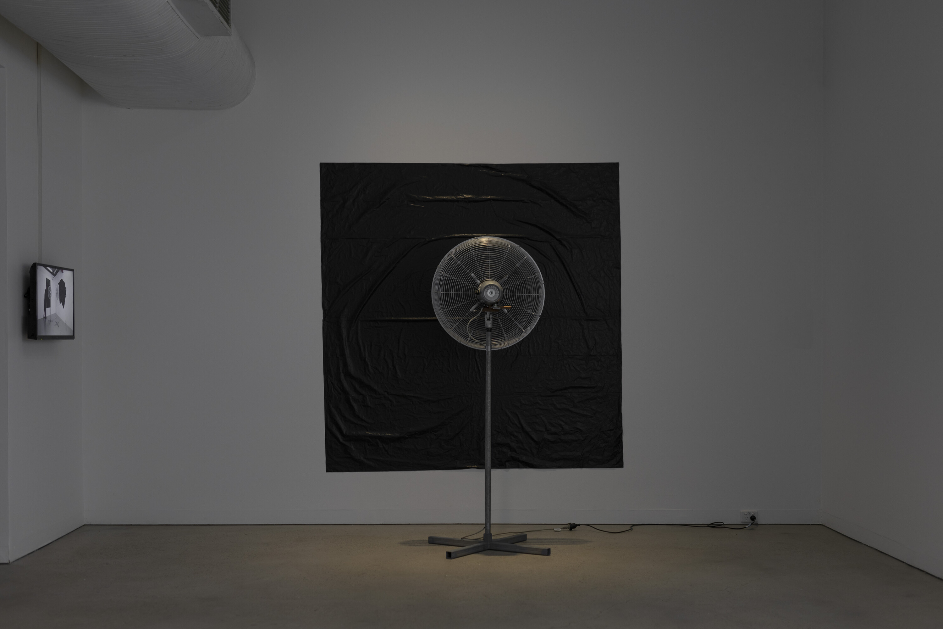 <p>Left: Denis Beaubois, <em>Two Fronts</em>—<em>A Document</em>, 2023, 4k video, filmed on location at Airspace Projects, duration: 18 minutes; Right: Denis Beaubois, <em>Two Fronts</em>, 2023, Industrial fans, builders plastic, Australian red cedar (impeding fan oscillation), air flow as fixing agent. Photo: Jessica Maurer</p>