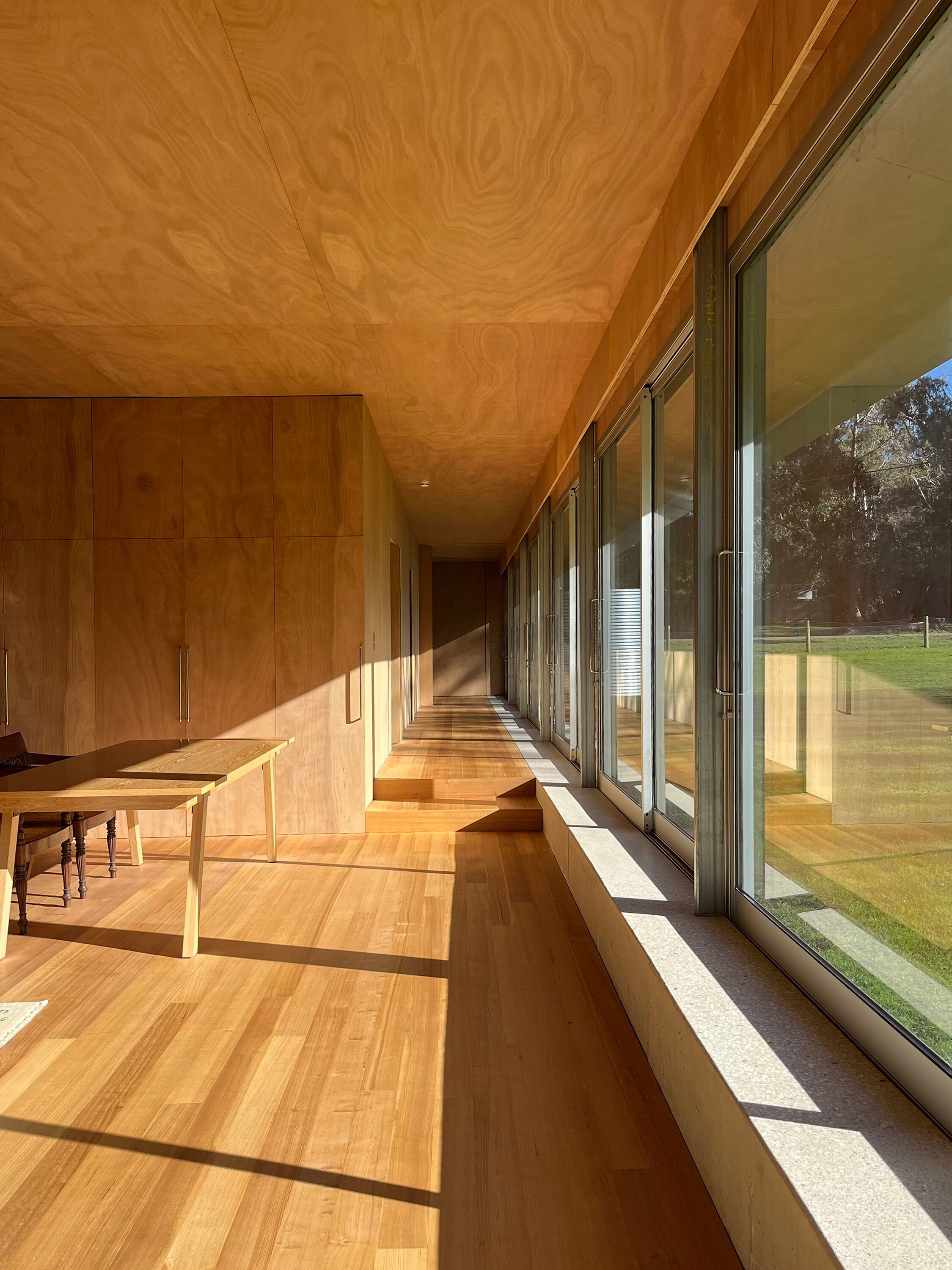 <p>Interior photograph showing the concrete element beneath the sliding doors; the “pelmet” can be seen above them, the floor can be seen stepping up, and the shadow cast by the eaves is visible. Courtesy of the architect.</p>