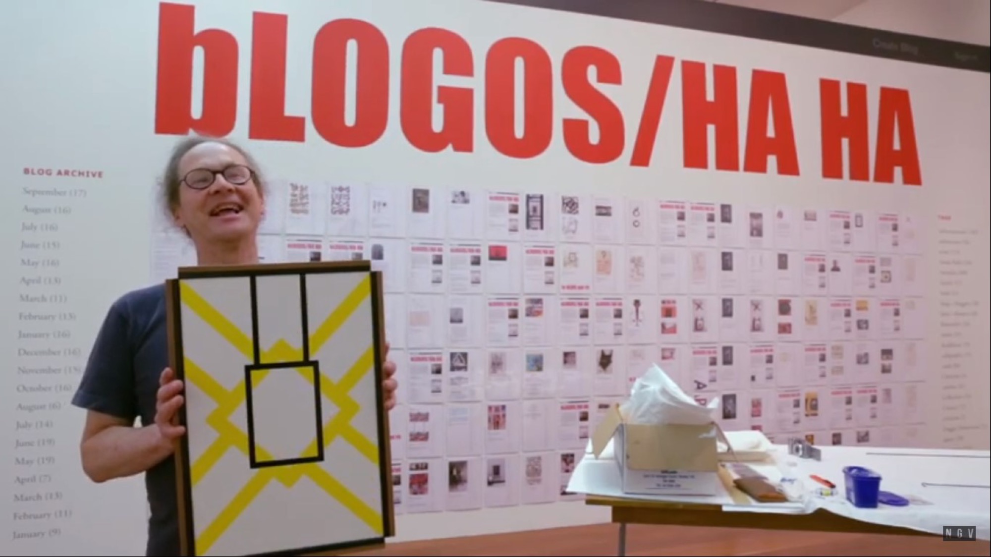Screenshot of National Gallery of Victoria video, of Peter Tyndall with his installation of <em>bLogos/HA HA</em> at <em>Melbourne Now</em>, 2014. <a href="https://www.youtube.com/watch?v=DjoSWnqagWg">Source</a>