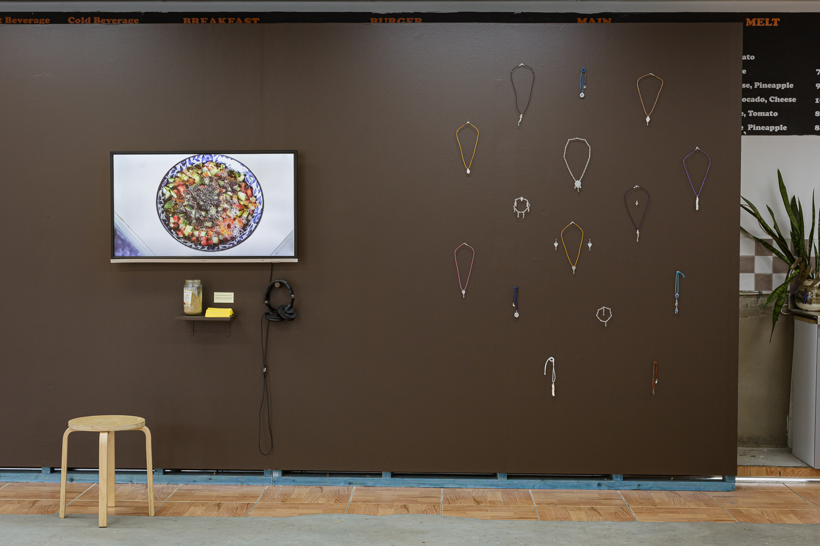 Left: Nadia Refaei, <em>Make Kabsah with Me</em>, 2020, single-channel video, glass, paper, cumin, ginger, cardamom, turmeric, black pepper, allspice, cinnamon, 13 min. Right: Mika Benesh, Amulets, 2022, sterling silver, glazed stoneware, ruby, amethyst, sapphire, blue topaz, citrine, peridot, rose quartz, green quartz, black spinel, 5 × 2cm, 9 × 3cm pendants. Photo: Document Photography.