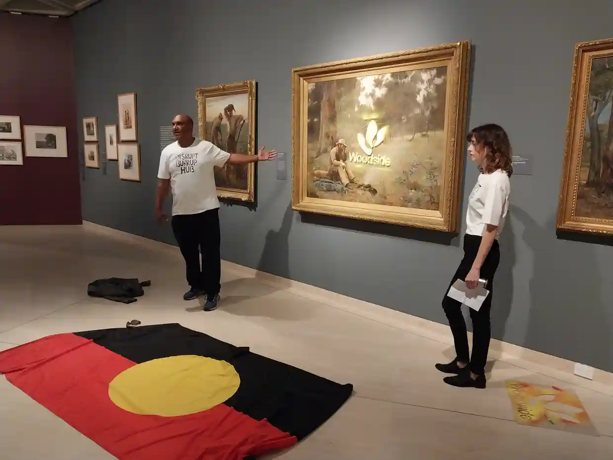 Protesters standing in front of the spray painted <em>Down on his luck</em> at the Art Gallery of Western Australia. Photograph: Disrupt Burrup Hub.